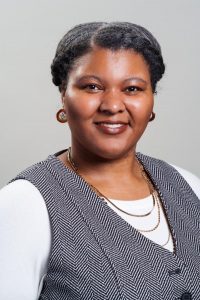 Photo of Linzy Andre, looking at camera, smiling, wearing Black and white clothing