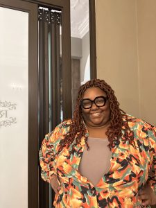 Photo of Atiya McGhee, smiling, and wearing brightly colored shirt